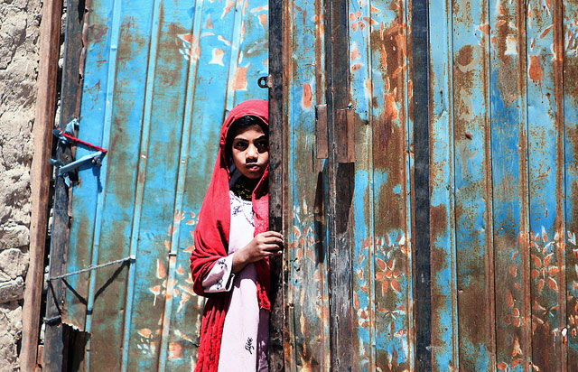 Afghan child peers around a door