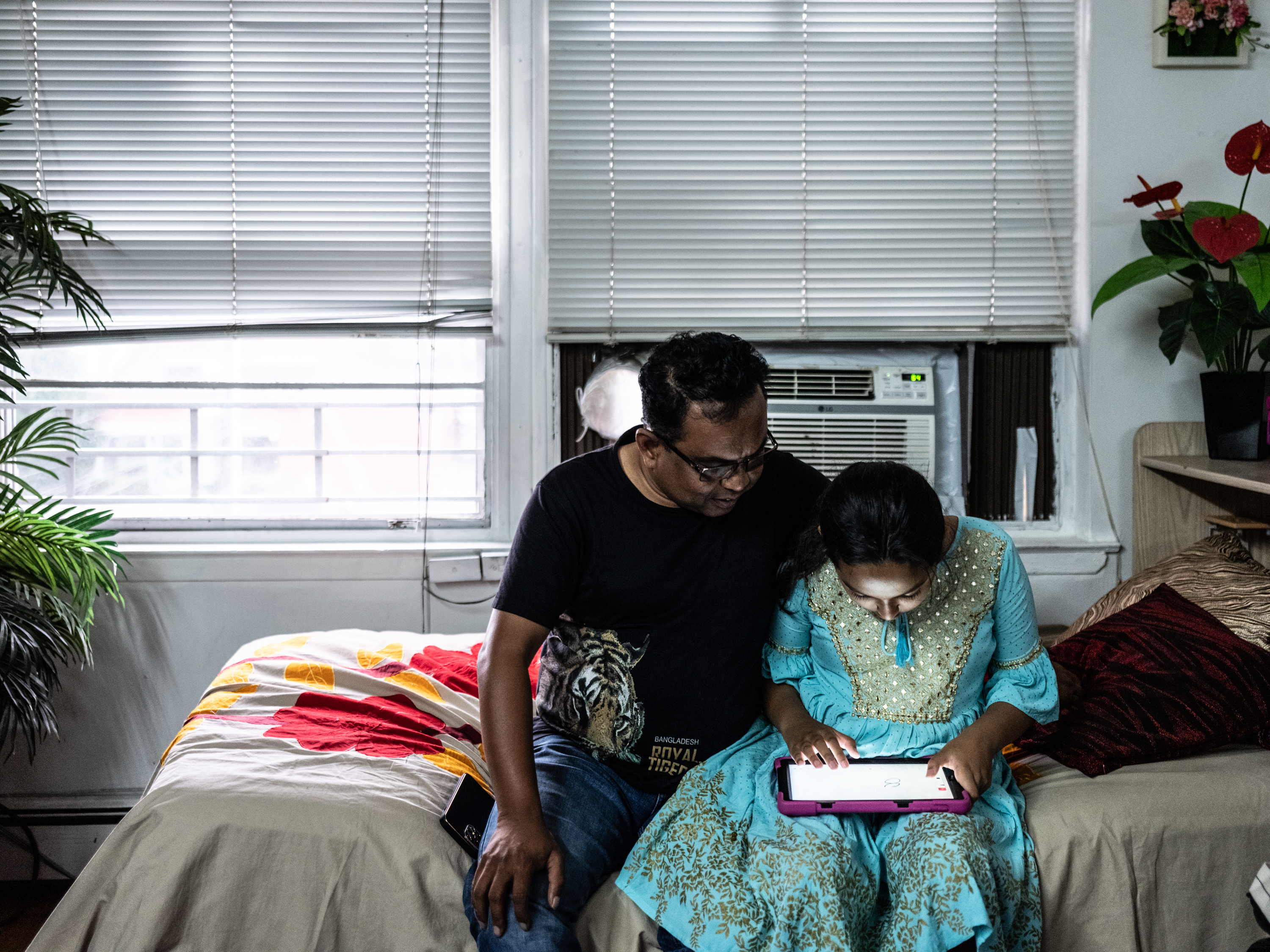 Mithu watches his daughter Nova drawing on her tablet in Jamaica, Queens in July 2022. 