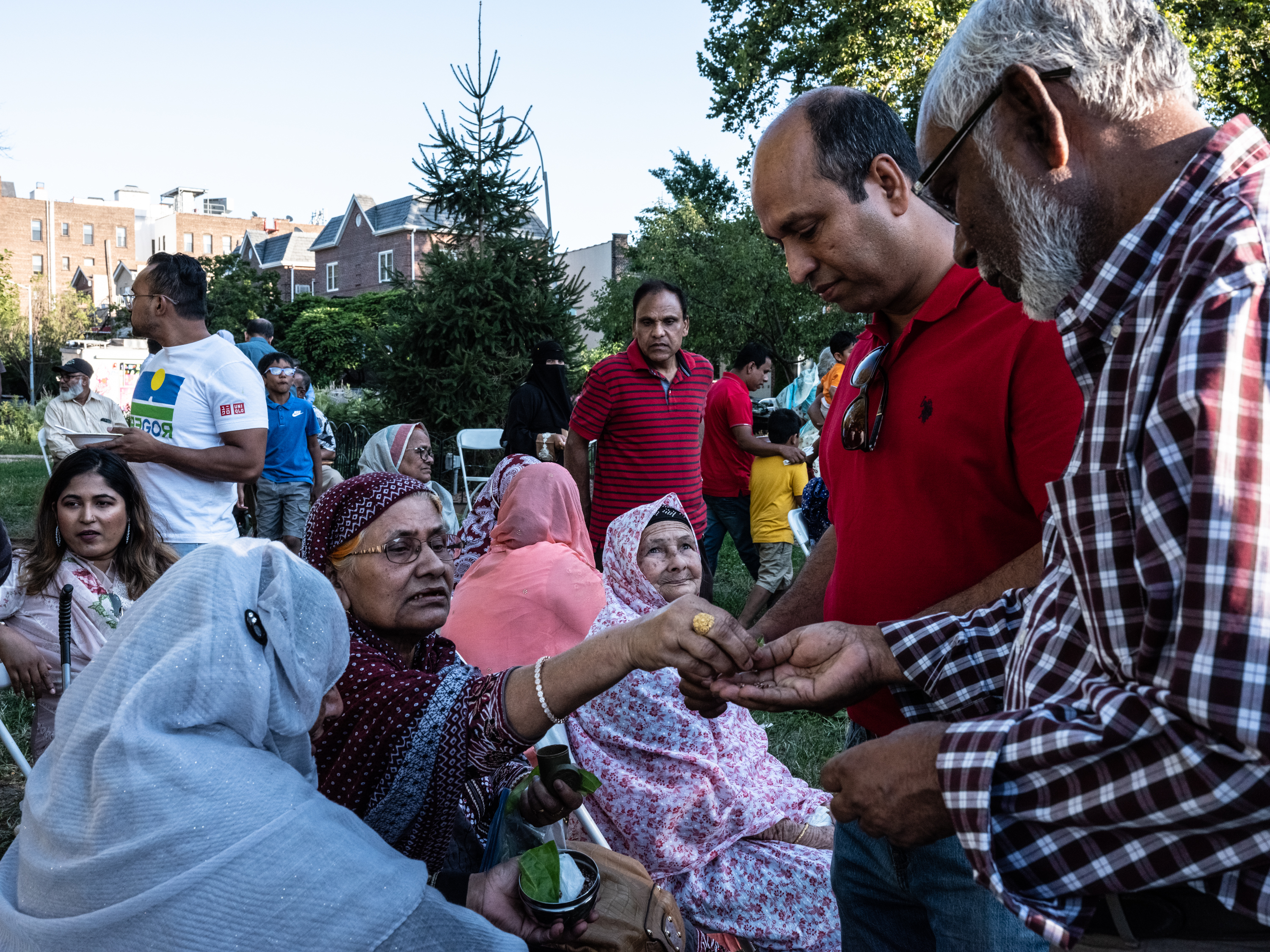Moin Choudhury, an immigration lawyer in who came to the United States to follow his parents and siblings shares betel leaves with Bangladeshi elders at a picnic in Astoria Park, Queens, in August 2022. 
