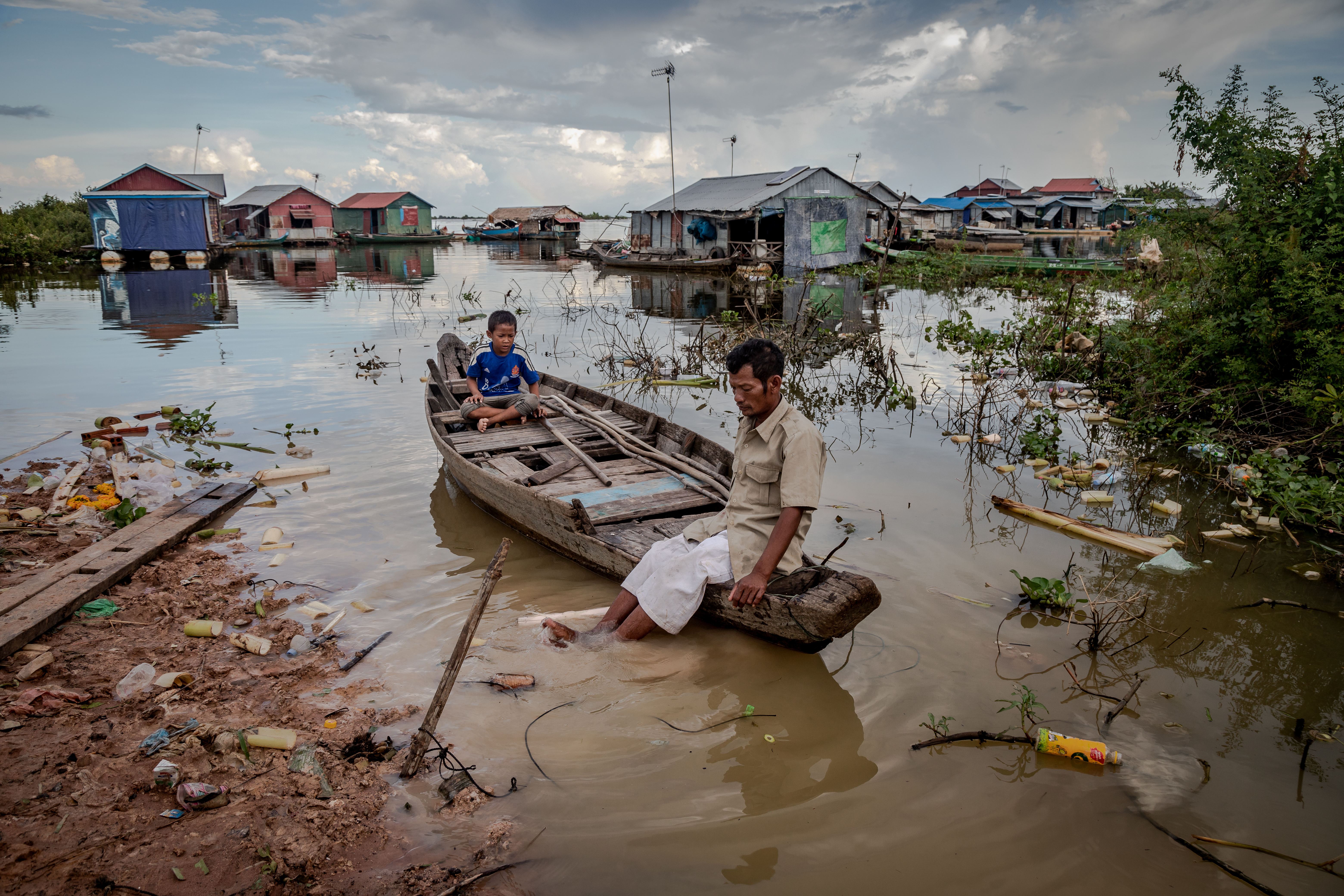 A fisherman and his son use a wooden boat to cross the water to get to their stilt house in Chong Kneas, Siem Reap, in October 2018.