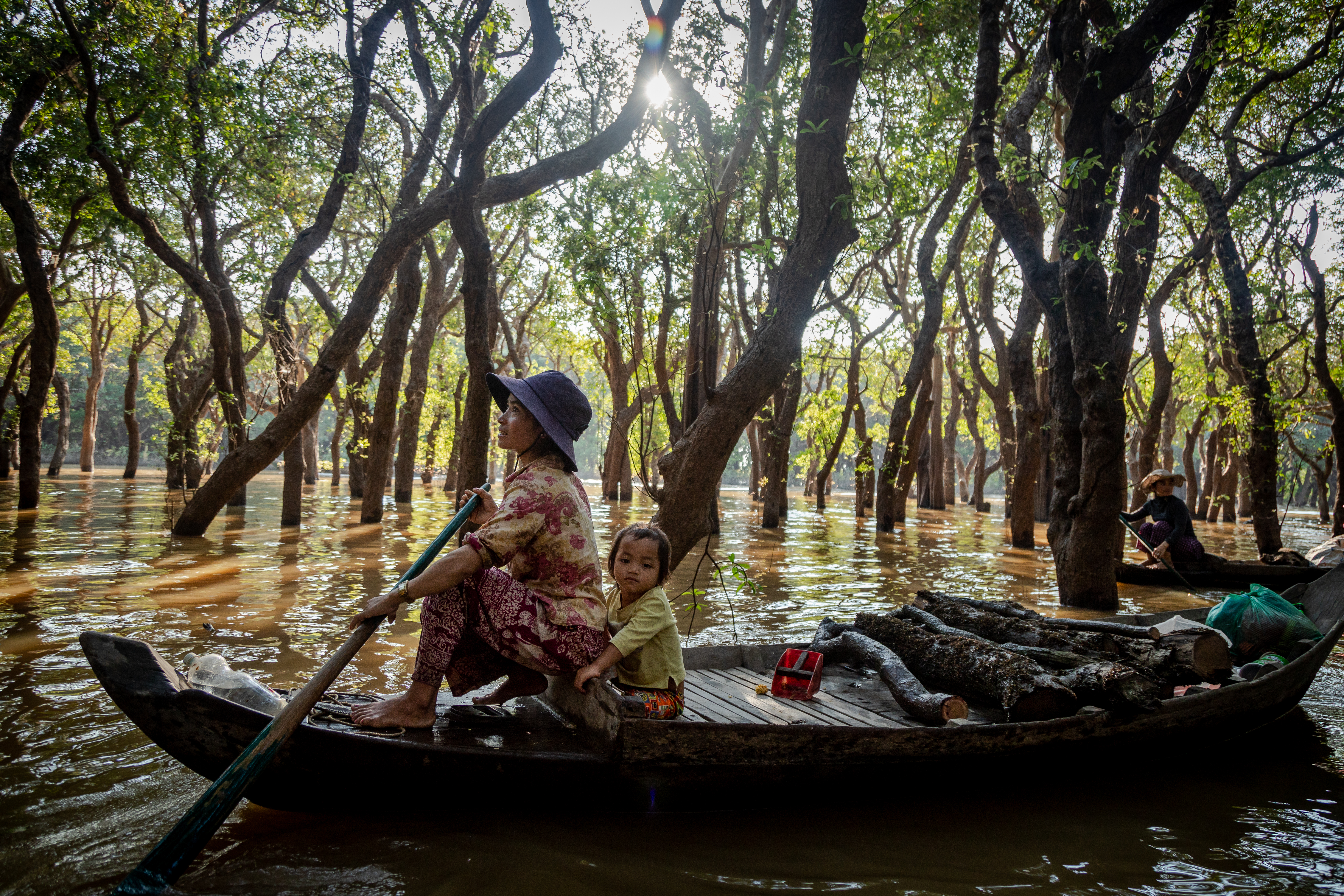 A mother and her daughter collect firewood in a flooded forest in Siem Reap's Kampong Phluk village in December 2018. 