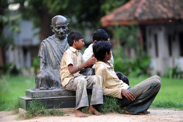 Indian boys sitting on the Mahatma Gandhi statue at the Gandhi Ashram in Ahmedabad in Aug. 2009. (Sam Panthaky/AFP/Getty Images)