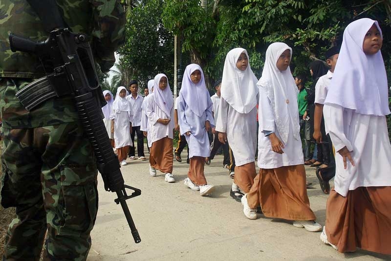 Thai Muslim school children walk past a soldier during a parade in the Takbai district of Thailand's restive southern province of Narathiwat, October 26, 2009. A bitter separatist insurgency in Thailand's Muslim-majority south has claimed more than 3,500 lives over the past five years. (Madaree Tohlala/AFP/Getty Images)