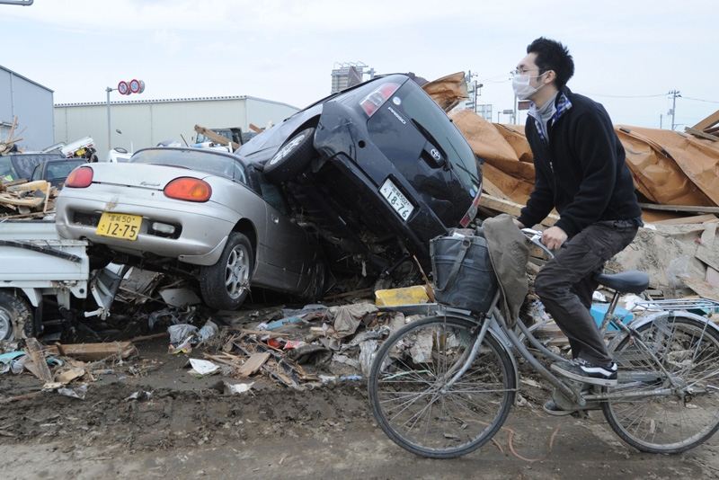 A man cycles past upturned cars and other tsunami-wrought devastation in Natori City, Miyagi prefecture, on March 14, 2011. (Mike Clarke /AFP/Getty Images)