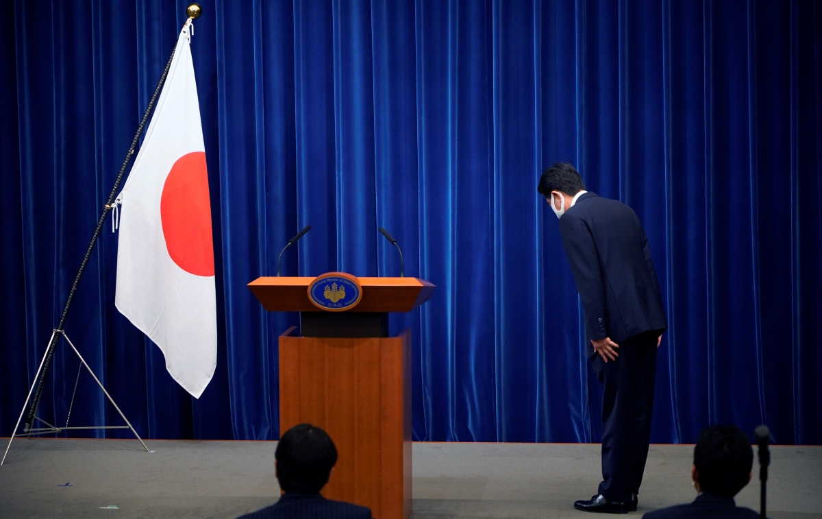 Japanese Prime Minister Shinzo Abe bows to the national flag at the start of a press conference announcing his resignation due to health concerns