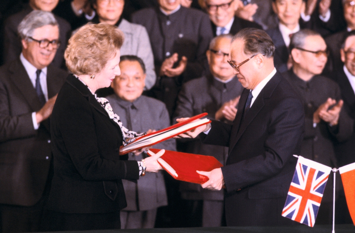 British Prime Minister Margaret Thatcher and Chinese Premier Zhao Ziyang exchange documents in Beijing during the signing of the Sino-British Joint Declaration on December 19, 1984 as Deng Xiaoping and others look on.