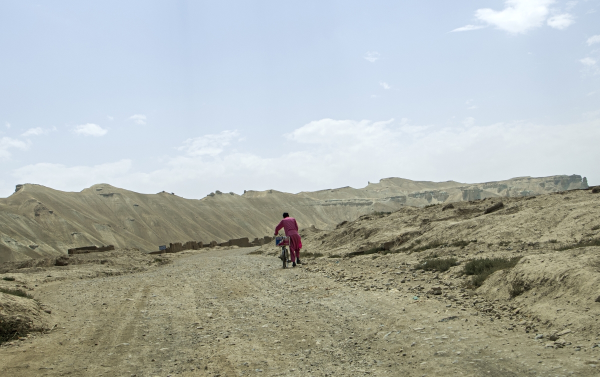 An Afghan man walks his bicycle down a barren path in Charkint district, Balkh province on June 29, 2021.