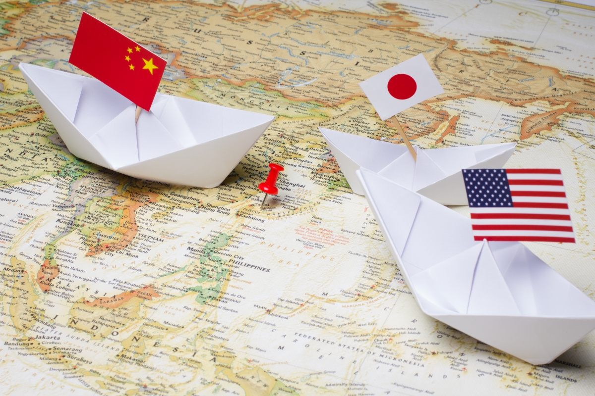 Paper boats with Chinese, Japanese, and American flags are poised over the Diaoyu Islands.