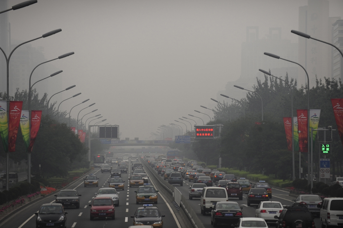 Cars drive through thick smog on a street in Beijing on Sept. 21, 2008, the first day of no traffic restrictions which limited motorists during the Olympic and Paralympic Games. (PETER PARKS/AFP/Getty Images)
