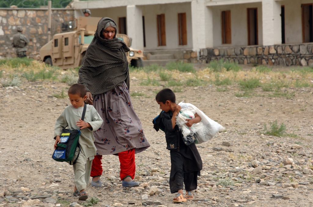 An Afghan woman walks home with her children carrying humanitarian goods after being seen by doctors with the Bagram Provincial Reconstruction Team during a medical civic action program in the district of Tagab in the Kapisa province of Afghanistan April 30, 2007. (Department of Defense)