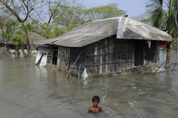 Moyna’s home in Bangladesh is completely surrounded by contaminated floodwater. Here, the 10-year-old is taking a bath – the only way she knows to try to keep clean. (Rafiqur Rahman Raqu/DFID/Flickr)