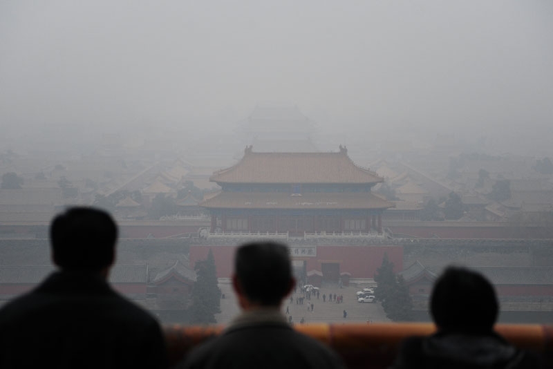 Tourists take in the view of the Forbidden City from atop Coal Hill in Jingshan Park, north of the former imperial palace on a smoggy day in Beijing on December 10, 2009. (Frederic J. Brown/AFP/Getty Images)