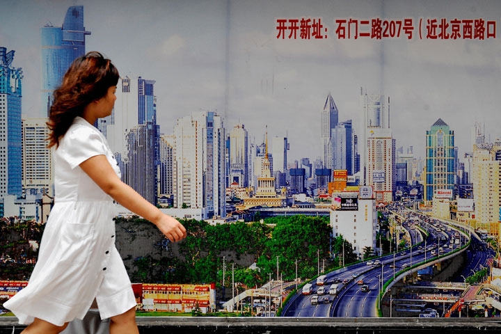 A woman walks past a billboard along a construction site in Shanghai on August 10, 2009. (Philippe Lopez/AFP/Getty Images)