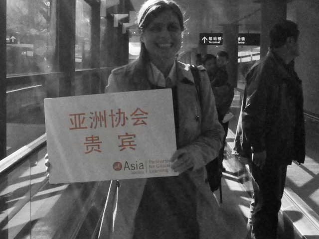 Eleise Jones holds up a sign at the Shanghai airport welcoming school leaders.