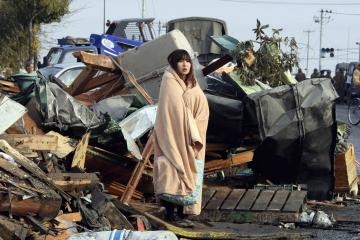 A survivor wrapped in a blanket stands to look on tsunami-damaged town at Ishinomaki city in Miyagi prefecture on March 13, 2011. (Yomiuri Shimbun/AFP/Getty Images)