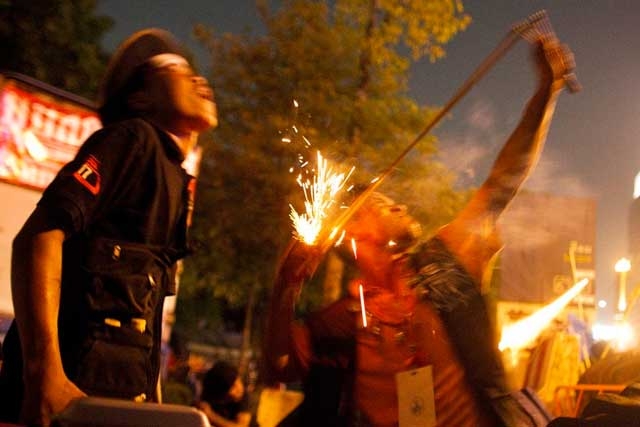 Red shirt protestors use a sling shot to launch a firecracker at Thai security forces from inside their encampment on May 13, 2010 in Bangkok. (Athit Perawongmetha/Getty Images)