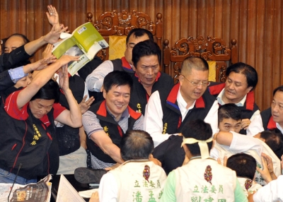 A book is thrown at a group of legislators from Taiwan's ruling Kuomintang party as they try to block their counterparts from occupying a podium at parliament in Taipei on July 8, 2010. (Patrick Lin/AFP/Getty Images)