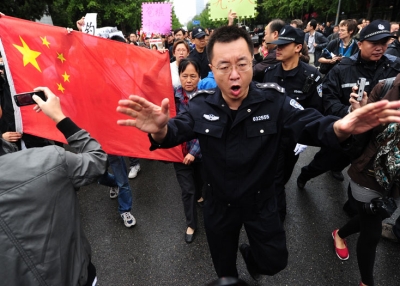 A policeman tries to disperse the crowd as anti-Japanese protesters shout slogans while marching through the embassy district in Beijing on September 18, 2010. More than a 100 anti-Japan protesters rallied in Beijing, furious over Tokyo's arrest of a Chinese fishing boat captain, a move which has sparked a major diplomatic row. (Frederic J. Brown/AFP/Getty Images) 