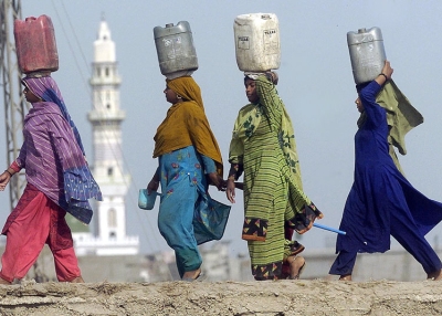 Pakistani women carry water in jerrycans on their heads in a slum area of Lahore. (Arif Ali/AFP/Getty Images)