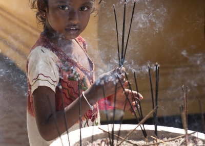 A child at a temple in Sri Lanka holding three sticks of incense in offering (three sticks being traditionally reserved for gods) on May 5, 2012. (Photosightfaces/Flickr)
