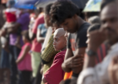 A young monk watches a street parade amidst a full crowd in Hikkaduwa, Sri Lanka on May 5, 2012. (Brett Davies/Flickr)