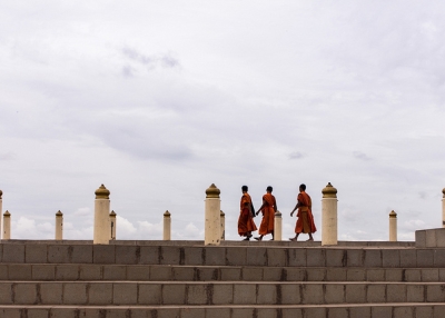 Three monks hurry across the stone steps under a cloudy sky in Vientiane, Laos on June 20, 2013. (Samuel Chan/Flickr)