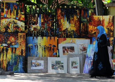 A woman walks past colorful paintings for sale on the roadside in Colombo, Sri Lanka on September 28, 2013. (Lakruwan Wanniarachchi/Getty Images)