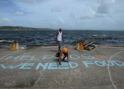 A man paints a message on a basketball court that reads "Help SOS We Need Food" in Tacloban, Philippines after the city was devastated by Super Typhoon Haiyan on November 11, 2013. (Noel Celis/AFP/Getty Images)