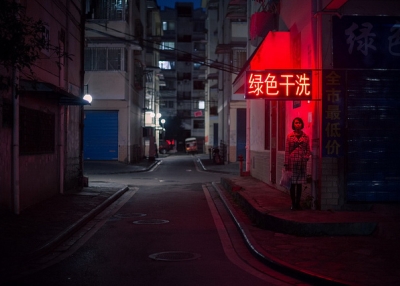 A woman stands under a red neon sign, in an empty street in Guilin, China on November 13, 2013. (金喜 刘/Flickr)
