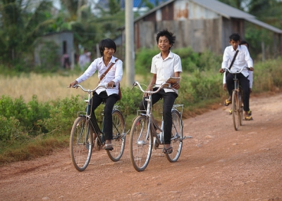 Students gleefully bike down a dirt road as they bike home from school on Fish Island, Cambodia on January 14, 2014. (Maciej Hrynczyszyn/ Flickr)