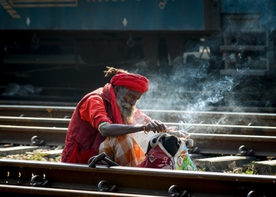 An old man sits between train tracks and lights a fire to keep warm in Bangladesh on December 31, 2013. (Rakib Hasan Sumon/Flickr)