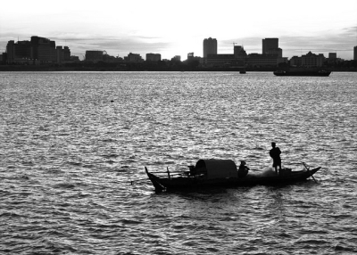 Two people in a boat stare at the city skyline in Cambodia on December 16, 2014. (ManJia Li/Flickr)