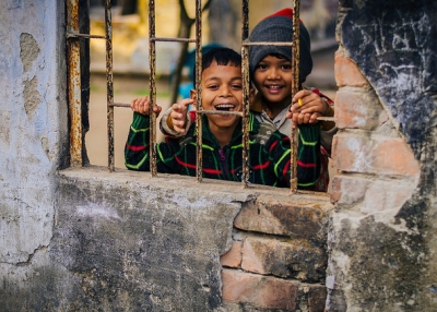 Two little boys smile through a window for a photograph in Faridpur, Bangladesh on January 18, 2015. (Rakib Hasan Sumon/Flickr)