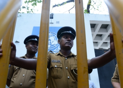 Sri Lankan policemen look on as Tamil pro-government activists take part in a demonstration outside the UN offices in Colombo on March 10, 2014, to protest a proposed US-led UN resolution to investigate Sri Lanka for alleged war crimes. (Lakruwan Wanniarachchi/AFP/Getty Images)