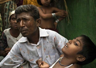 Roshida Moud, 12, is held by his father as the latter explains that his son was hit in the head with a stone during the Rakhine violence in 2012, in Sittwe, Myanmar, on May 6, 2014. (Andre Malerba/Getty Images)