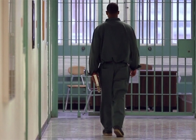 Inmate in New York State carries a book through a prison corridor. (Bard Prison Initiative promotional film screen grab; Winton/duPont Films)
