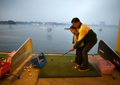 A father teaches his son how to golf at the Hanoi club golf center March 10, 2011 in Hanoi, Vietnam. (Paula Bronstein/Getty Images)