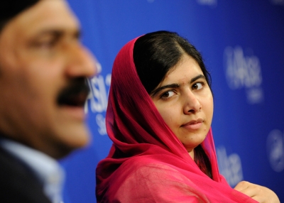 Malala Yousafzai listens as her father, Ziauddin Yousafzai, addresses attendees at Asia Society In New York