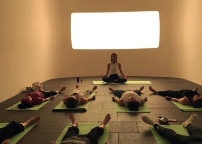 People doing yoga in front of a light art installation.