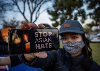 Julie Tran holds her phone during a candlelight vigil in Garden Grove, California, on March 17, 2021 to unite against the recent spate of violence targeting Asians and to express grief and outrage after yesterday's shooting that left eight people dead in Atlanta, Georgia, including at least six Asian women.