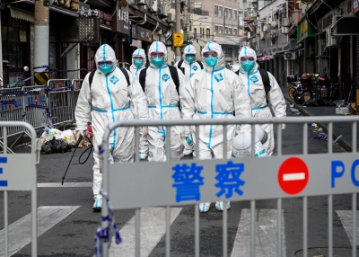 Health workers in protective gear walk out from a blocked off area after spraying disinfectant in Shanghai's Huangpu district on January 27, 2021, after residents were evacuated following the detection of a few cases of COVID-19 coronavirus in the neighbourhood.