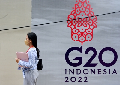 A woman walks past a logo of the G20 Summit, in Jakarta on November 8, 2022.