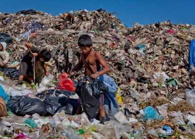 Three refugee children work together at the dump in Mae Sot, Thailand. The child on the left is just seven years old and recently received a pair of gumboots. (Jacques Maudy)