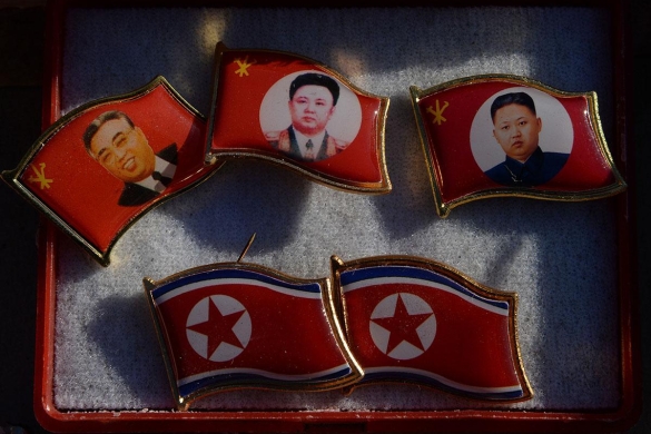 Badges showing late North Korean leaders (L-R) Kim Il Sung and Kim Jong Il and new leader Kim Jong Un for sale by a street vendor in the Chinese border town of Dandong.