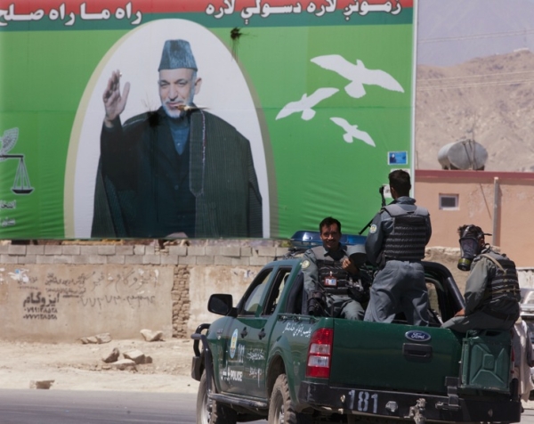 A day before the vote, on August 19, Afghan National police drive by a massive billboard of President Karzai at a Kabul traffic circle. (Paula Bronstein/Getty Images)