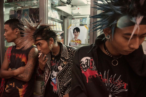 In Yangon, members of the punk group Rebel Riot rest outside a newsstand with a poster of opposition leader Aung Sun Suu Kyi on July 3, 2012. (Gilles Sabrié)
