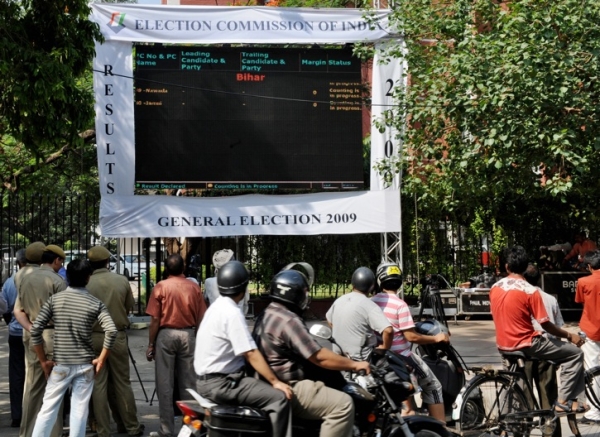 Pedestrians and commuters watch as election results are displayed on a giant display screen in front of the Election Commission of India (ECI) head office in New Delhi on May 16, 2009. (Raveendran/AFP/Getty Images)