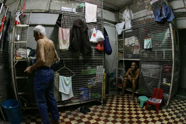 Mr Kong (R) a cage dweller sits in a cage on June 20, 2007 in Hong Kong, China. The poorest of Hong Kong's citizens live in cage homes, steel mesh box constructions, stacked on top of each other. (MN Chan/Getty Images)