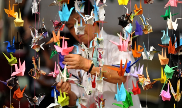 An artist hangs origami before International Day of Peace celebrations at the Quezon City Memorial Circle, east of Manila on September 21, 2010.