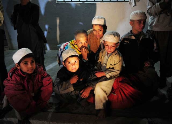 Young Pakistani students sit after being rescued following a police raid on Madrassa Zakarya in Karachi late on December 12, 2011. (ASIF HASSAN/AFP/Getty Images)